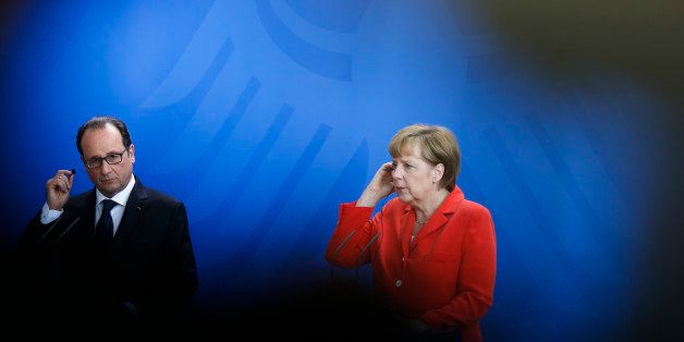 In this photo taken through a gap between a television cameraman and the camera German Chancellor Angela Merkel, right, and French President Francois Hollande brief the media after a meeting at the chancellery, in Berlin, Germany, Tuesday, May 19, 2015. (AP Photo/Markus Schreiber)
