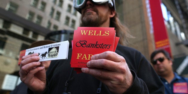 SAN FRANCISCO, CA - APRIL 23: A protestor holds a sign during a demonstration outside of the Wells Fargo headquarters on Apr