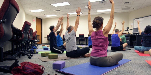 CAMBRIDGE, MA - JUNE 3: Noon office yoga class at Draper Laboratory, one of Draper's employee wellness initiatives. Draper is a Cambridge research lab that also promotes diversity by offering transgender health services and other benefits through its insurance, Harvard Pilgrim Health Care. Draper executives say honoring employee diversity and wellness is part of their mission. (Photo by Joanne Rathe/The Boston Globe via Getty Images)