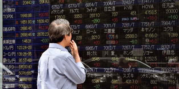 An investor gazes at a share prices board in Tokyo on June 11, 2015. Japan's share prices rose 336.61 points to close at 20,3
