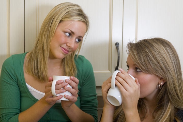 Two beautiful young women chatting over a warm drink.