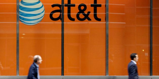 In this Tuesday, Oct. 21, 2014 photo, people pass an AT&T store on New York's Madison Avenue. AT&T says it will buy Mexican wireless company Iusacell for $2.5 billion including debt and says it plans to grow in Mexico. (AP Photo/Richard Drew)