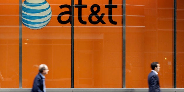 In this Tuesday, Oct. 21, 2014 photo, people pass an AT&T store on New York's Madison Avenue. AT&T says it will buy Mexican wireless company Iusacell for $2.5 billion including debt and says it plans to grow in Mexico. (AP Photo/Richard Drew)