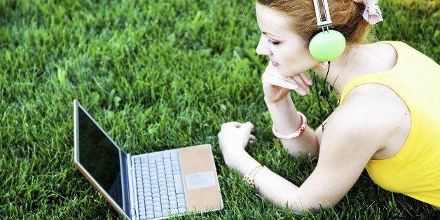 Young woman having rest on grass with laptop