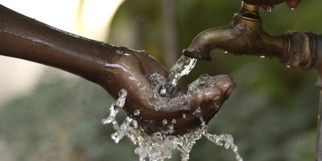 Hand of an African child with water pouring from a tap.
