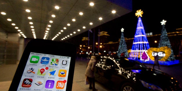 The Uber app is displayed on a phone posed for photos near a woman peering into a car outside a office building in Beijing, F