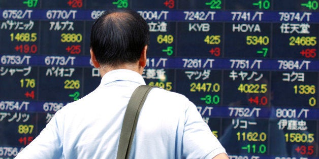 A man looks at an electronic stock indicator of a securities firm in Tokyo, Tuesday, Aug. 11, 2015. Tokyo stocks gave up earl