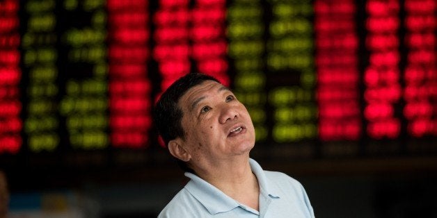 An investor monitors screens showing stock market movements at a brokerage house in Shanghai on August 13, 2015. Shanghai shares were down 0.62 percent, 24.26 points to 3,862.06, by the break on August 13, after China set a lower value for its yuan currency for the third straight day. China cut the reference rate for its currency for the third straight day on August 13, authorities said, after their surprise devaluation of the yuan this week unsettled global financial markets. AFP PHOTO / JOHANNES EISELE (Photo credit should read JOHANNES EISELE/AFP/Getty Images)