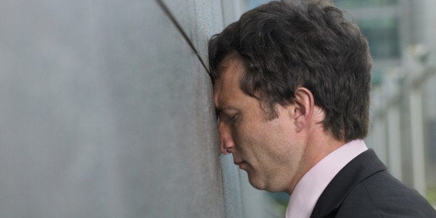 Businessman with face pressed against wall, profile, close-up