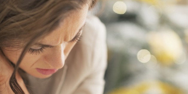 Stressed young woman in front of christmas tree