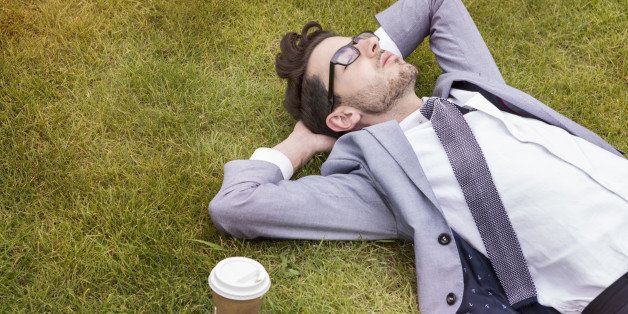 business person having break, laying in park.