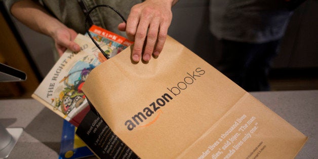 An employee puts books in a bag for a customer at the Amazon Books store in Seattle, Washington, U.S., on Tuesday, Nov. 3, 2015. Amazon.com Inc.'s store lets shoppers pick up books and try the online retailer's gadgets, including the Fire TV streaming device, Fire tablet and Kindle electronic reader. Photographer: David Ryder/Bloomberg via Getty Images