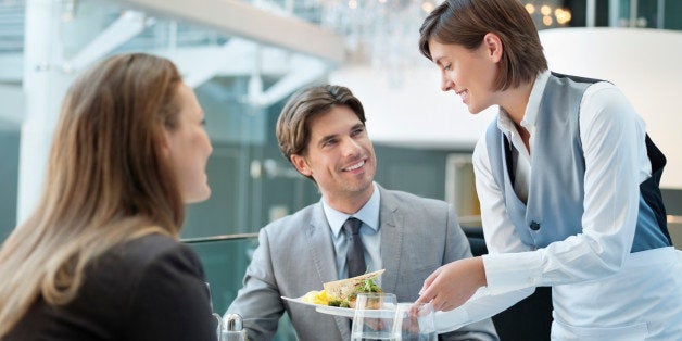 Waitress serving food to couple in restaurant