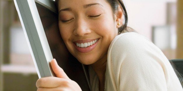 Pacific Islander businesswoman hugging computer monitor