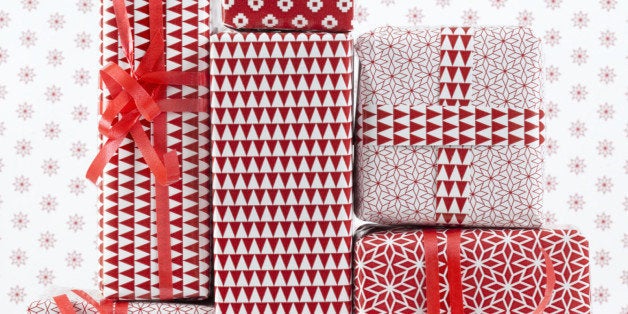 Stack of red patterned wrapped presents, by red patterned background