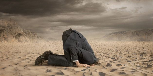 Young businessman hiding head in the sand