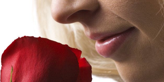 Side profile of a young woman smelling a rose