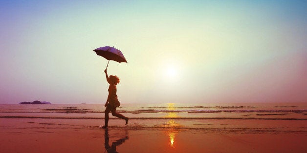 happy woman jumping with umbrella on the beach