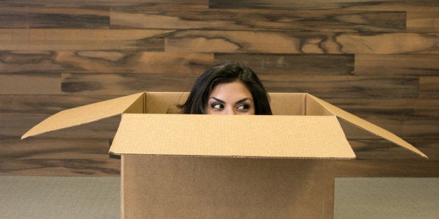 Mixed race woman hiding in cardboard box