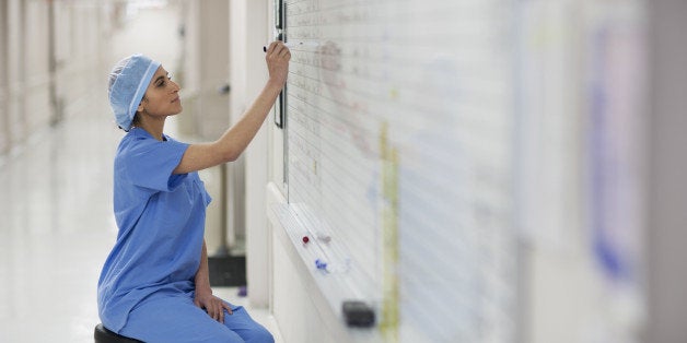 Hispanic nurse writing on whiteboard in hospital