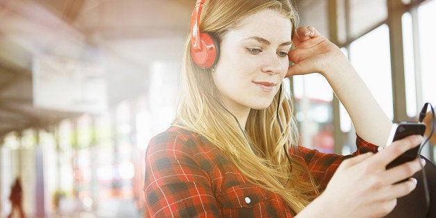 woman at station listening to music with mobile