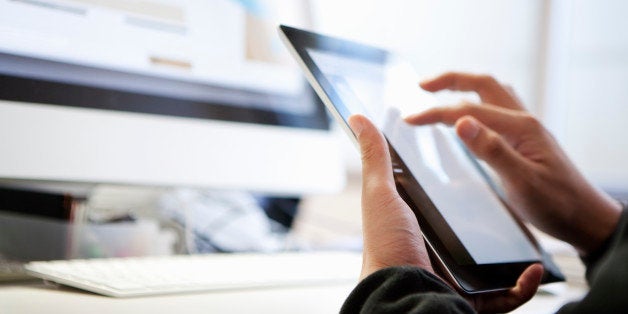 Hands of a web designer using a digital tablet, he is working with a desktop computer.