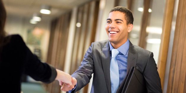 young man arrives at his interview , resume under his arm greeting his interviewer