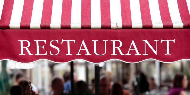 Typical restaurant scene in Paris with tables and chairs arranged on the street covered with an awning.