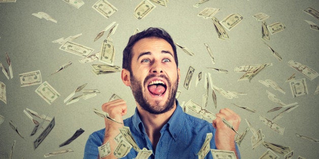 Portrait happy man exults pumping fists ecstatic celebrates success screaming under money rain falling down dollar bills banknotes isolated gray background with copy space. Financial freedom concept