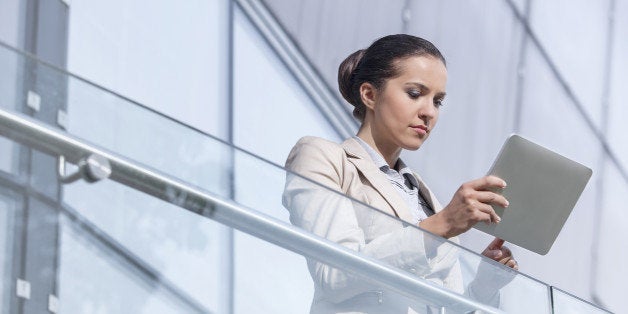 Beautiful young businesswoman using digital tablet at office railing
