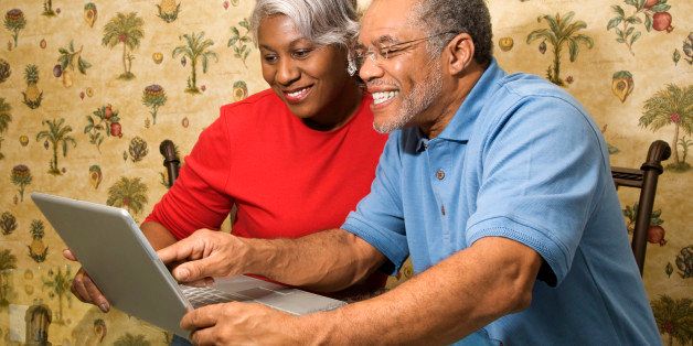 Portrait of mature African American couple looking and smiling at laptop in home.