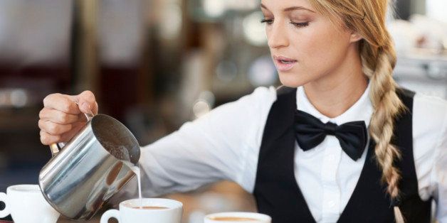 Denmark, Aarhus, Female barista pouring milk into coffee cup
