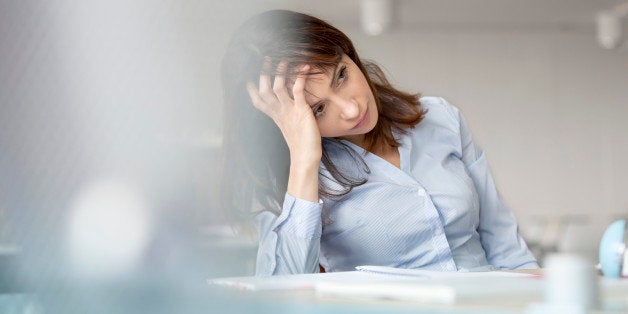 Tired businesswoman with head in hands looking away