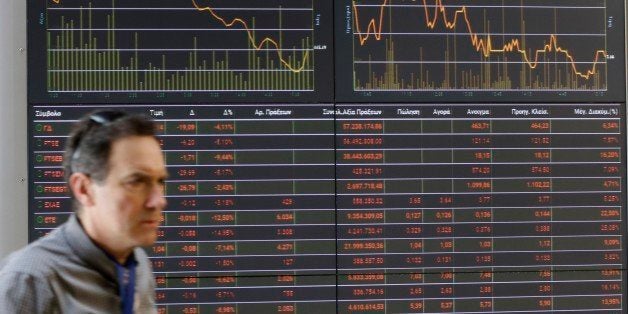 A man passes an index board at the reception hall of the Stock Exchange in Athens, Tuesday, Feb. 9, 2016. Greece is expected