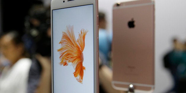 In this Sept. 9, 2015 photo, people look over the new Apple iPhone 6s models during a product display following an Apple event in San Francisco. Photography gets even better with Apple's new iPhones, making them worth getting for $100 more than last year's models.(AP Photo/Eric Risberg)