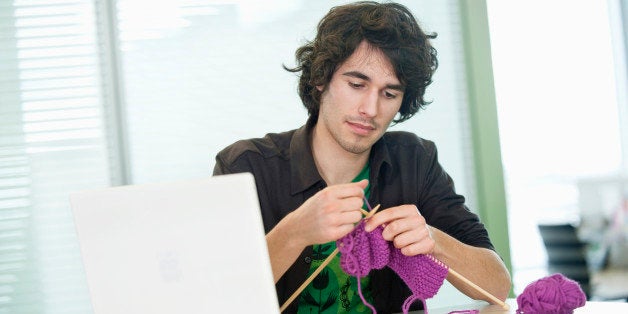 Businessman knitting in front of a laptop