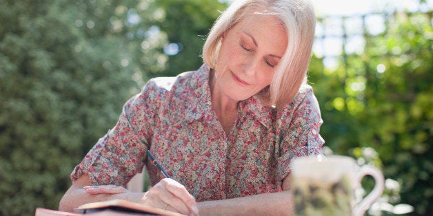 Woman writing in journal at patio table