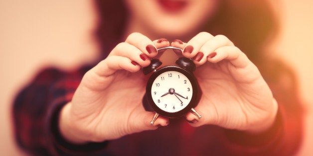 Portrait of a young caucasian girl in glasses with Clock on pink background.