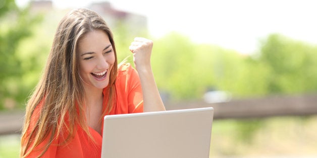 Euphoric woman searching job with a laptop in an urban park in summer