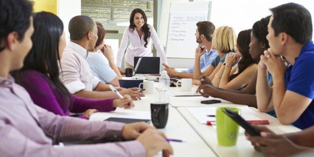 Businesswoman Addressing Meeting Around Boardroom Table In Smart/Casual Dresswear