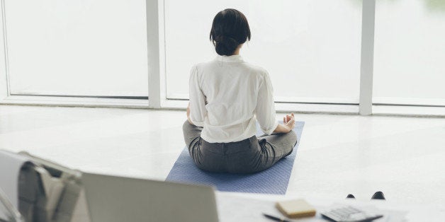 Office worker meditating on the floor, rear view