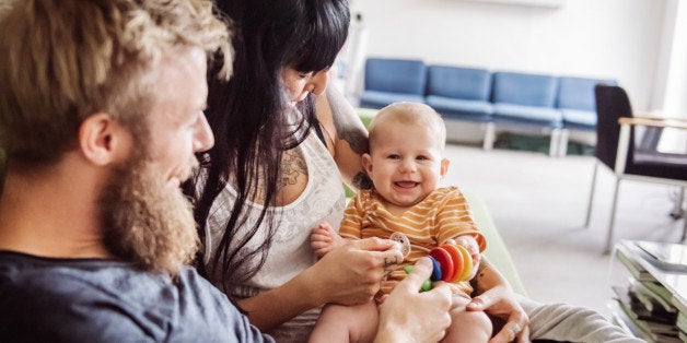 Young couple at home relaxing with their new born child on couch