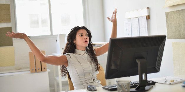 Mixed race businesswoman frustrated at computer at desk in office