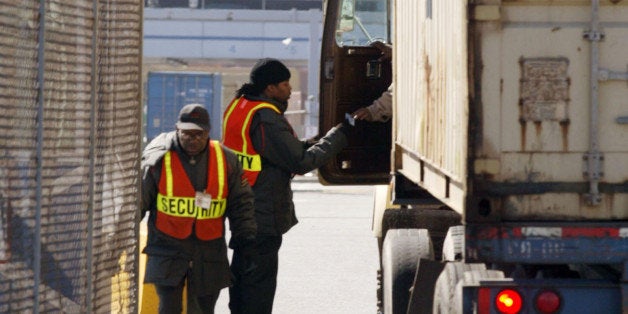 Security personnel check with the driver of a tractor trailer at the main gate entrance to the Seagirt Terminal in Baltimore, Maryland February 24, 2006. A rally by the Teamsters Union was held across the street from the terminal to protest the sale of U.S. ports operation to Dubai Ports World. REUTERS/Joe Giza