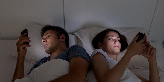 Young couple with smartphones in their bed