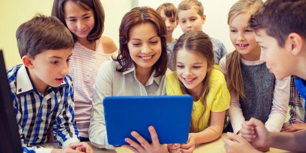 education, elementary school, learning, technology and people concept - group of school kids with teacher looking to tablet pc computer in classroom