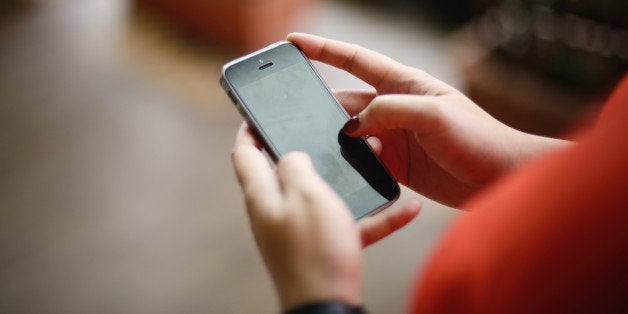 Close up shot of woman's manicured hand as she uses a handphone