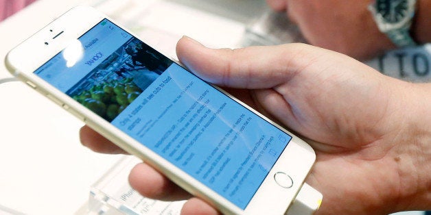 FILE - In this Sept. 19, 2014, file photo, a customer looks at the screen size on an iPhone 6 Plus while waiting in line to u
