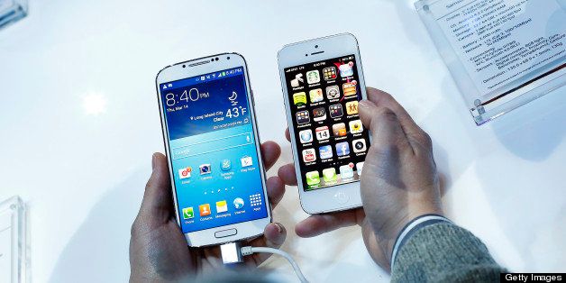 An attendee holds a Samsung Electronics Co. Galaxy S4 smartphone, left, next to an Apple Inc. iPhone 5 during an event at Radio City Music Hall in New York, U.S., on Thursday, March 14, 2013. Samsung unveiled the Galaxy S4 with a bigger screen and software that tracks eye movements as the world's biggest smartphone seller takes its battle with Apple Inc. to the iPhone maker's home market. Photographer: Victor J. Blue/Bloomberg via Getty Images