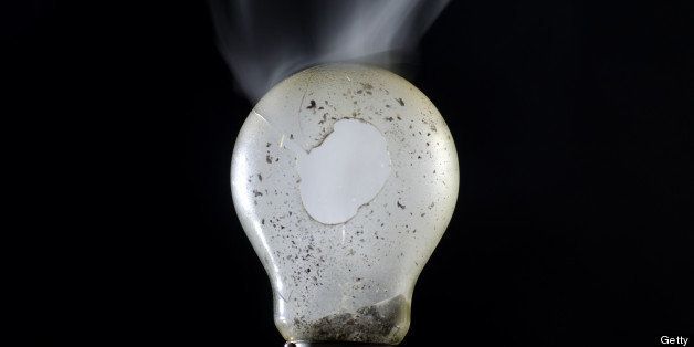 Broken lamp bulb with smoke in black background.
